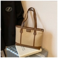 Close-up of woven tote bag with brown leather trim resting on a silver suitcase - Khaki