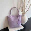 Minimalist light purple nylon handbag with heart pendant on a white book display - Purple