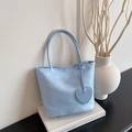 Minimalist sky blue nylon tote bag with heart charm and slim handles on white books - Blue