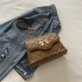 Quilted brown crossbody bag with gold bow buckle and chain strap on denim - Brown