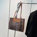 Chic leopard print tote bag with brown leather straps hanging on a silver hanger - Brown