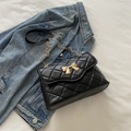 Classic black quilted crossbody bag with golden bow clasp and chain strap on denim fabric - Black