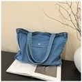 Detailed close-up of blue denim tote bag with gold metal snap button and front pocket - Light Blue