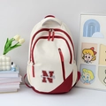 Mochila estilo campus beige y granate con logo N en escritorio con flores frescas - Rojo
