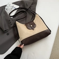 Bolso tote de lona y cuero marrón con hebilla dorada sobre fondo de chaqueta gris - Caqui