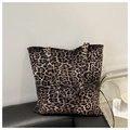 Close-up of leopard print tote bag fabric texture on a leather chair background - Coffee