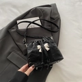 Black pleated bucket bag featuring a large silver bow and adjustable shoulder strap - Black