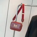Red crossbody box bag with glossy pleated finish and golden bow clasp on wide strap - Red