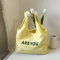 Borsa tote in raso giallo con scritta AREYOU nera in un ambiente minimalista - Giallo