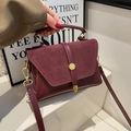Detail of burgundy crossbody bag with matte flap, round metal lock, and top handle - Red
