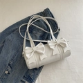 Schicke weiße Zylindertasche mit doppelten 3D-Schleifen auf blauem Denim-Hintergrund - Weiß