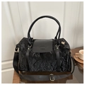 Close-up of black pleated travel bag featuring gold hardware and logo-embossed leather flap - Black