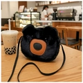 Detailed close-up of a black plush bear cross-body bag on a rustic wooden table - Black