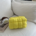 Quilted bright yellow makeup bag with square stitching on a white sofa with headphones - Yellow