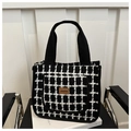 Détail du sac cabas à carreaux avec poignées tissées et écusson en cuir brun - Grille Noire