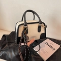 Classica borsa Boston in pelle bianca e nera con ciondolo in corda intrecciata su sfondo scuro - Bianco & Nero