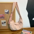 Detalle de un bolso bandolera de media luna rosa claro en nailon texturizado sobre corcho - Rosa