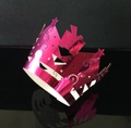 Detail van rose rode metalen cake wrap met ingewikkelde lasergesneden ster- en spiraalpatronen - Reflecterend Rozerood