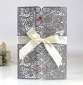Close-up of glittery silver laser-cut floral wedding invitation with silk bow decoration - Glitter Charcoal Silver