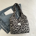 Grey leopard print plush tote bag with brand label on a textured flat lay backdrop - Black