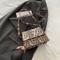 Elegant leopard print crossbody bag with gold hardware on a gray blazer backdrop - Brown
