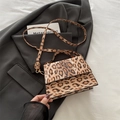 Leopard print crossbody flap bag with top handle and gold hardware on black suit - Brown