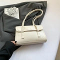 Elegante bolso de hombro en cuero blanco crema con solapa sobre fondo de traje gris - Blanco