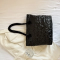 Elegante borsa tote nera con trapuntatura a stella e manici intrecciati in posa flat - Nero