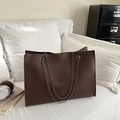 Borsa tote marrone scuro in pelle martellata con catene argentate in un ambiente moderno - Marrone