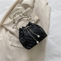 Bolso tipo cubo acolchado negro con dijes de perlas y cadena sobre blazer beige - Negro