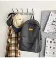Minimalist dark gray canvas backpack with orange logo label in lifestyle setting - Gray