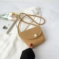 Detail of hand-woven straw crossbody bag featuring a large pearl embellishment on the flap - Khaki