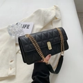 Elegante borsa a tracolla nera trapuntata con catena dorata su sfondo lifestyle raffinato - Nero