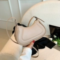 Elegante bolso hobo beige de cuero liso con correa ajustable en un sofá blanco - Caqui