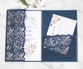 Detailed macro view of navy laser-cut lace wedding invitation with floral insert - Dark Blue