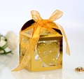 Close-up of golden hollow candy box with Love engraving and orange silk ribbon - Reflective Gold