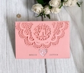 Pink laser-cut wedding invitation card with lace patterns and bird design on wood surface - Pink
