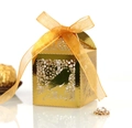 Macro view of golden laser-cut candy box with bird patterns and an orange ribbon bow - Reflective Gold