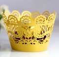 Close-up of yellow laser-cut lace cupcake wrapper with intricate floral patterns - Gold