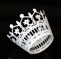 Detail of white laser-cut cupcake wrapper with a crown design on a dark background - White