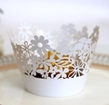Close-up of white laser-cut cupcake wrapper with daisy floral pattern on a porcelain plate - White