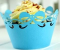 Close-up of laser-cut blue cupcake wrappers with bow-knot lace and scallop edge pattern - Sky Blue