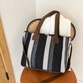 Vertical striped black and white canvas tote bag with brown straps on vintage chair - Black