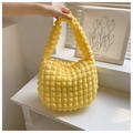 Detalle del bolso de mano amarillo con burbujas y textura en relieve sobre fondo minimalista - Amarillo