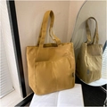 Dettaglio di una borsa tote in tela giallo zenzero con tasche frontali ed etichetta logo - Cachi