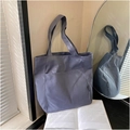 Dettaglio della borsa tote in tela grigio-blu con tasca frontale ed etichetta nera - Blu