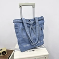 Borsa tote in denim blu con ricamo Street Seven and Six su una valigia bianca - Blu