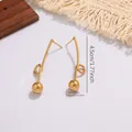 Detail view of geometric drop earrings featuring a long curved bar and golden ball charm - Minimalist Ball Long Style (E2037)