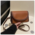 Detailed macro view of brown lychee grain leather handbag with gold logo and contrast piping - Tan