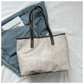 Bolso tote beige en cuero agrietado con asas marrones sobre fondo denim azulado - Café sin colgante